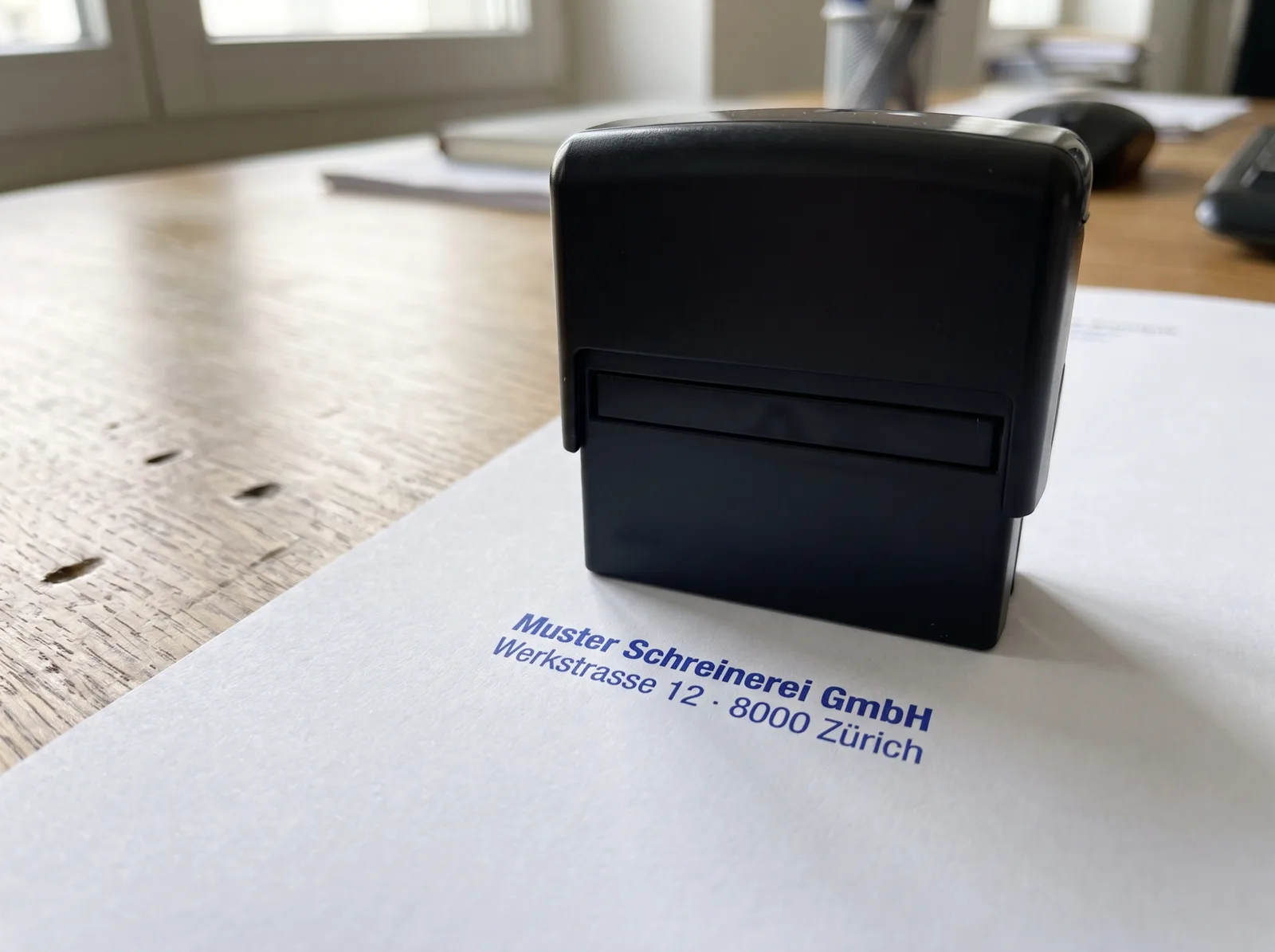 Selbstfärbender Stempel, daneben ein blauer Firmenstempel-Abdruck